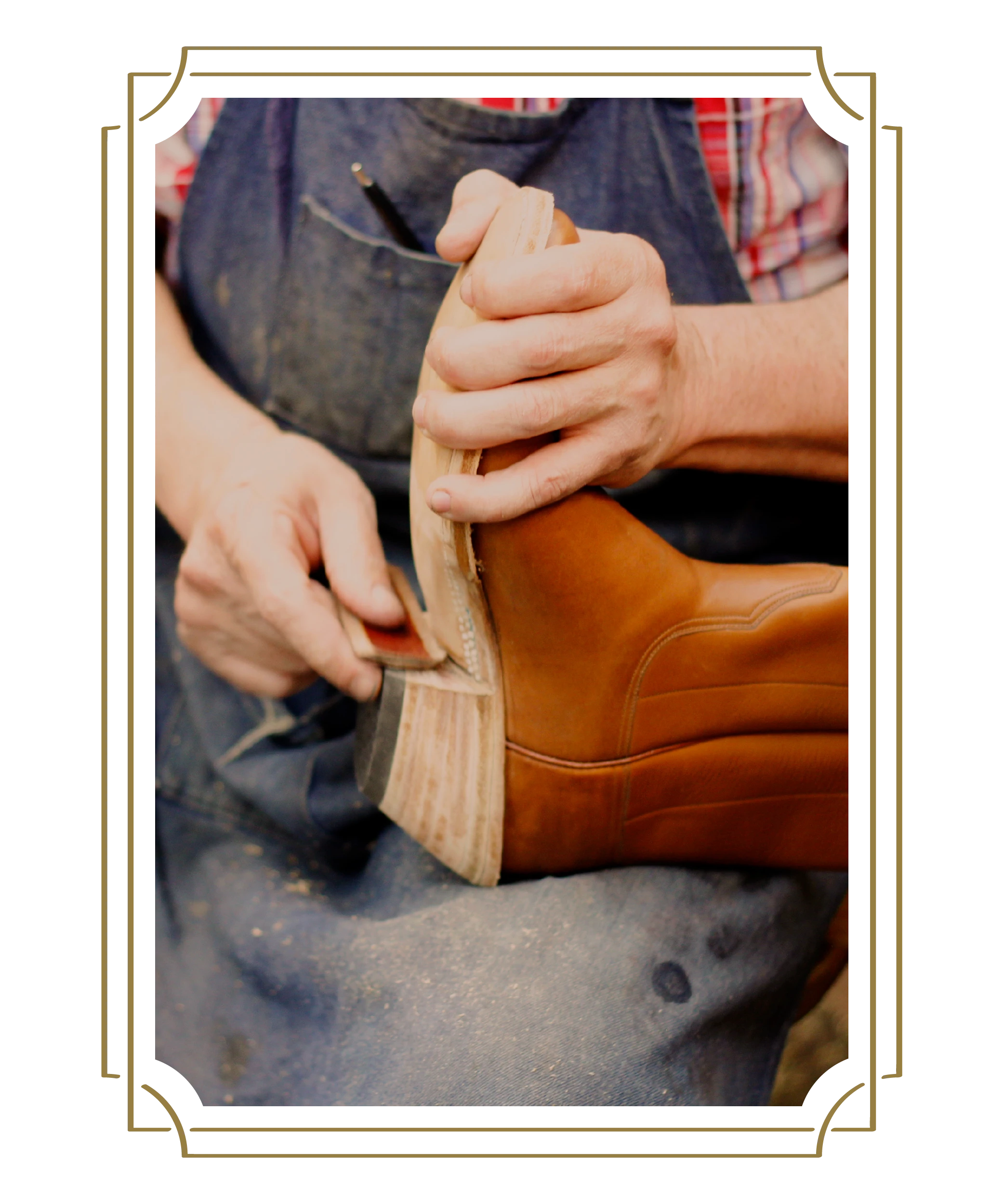 A person in a blue apron is taking care of a pair of homemade cowboy boots.