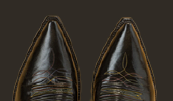 Close-up view of the pointed toes of a pair of personalized luxury cowboy boots with intricate stitching detail on a dark background.