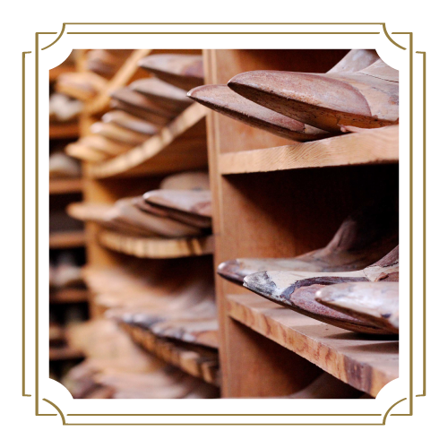 Rows of wooden shoe lasts, designed for crafting personalized luxury cowboy boots, are placed meticulously on shelves in a storage area.