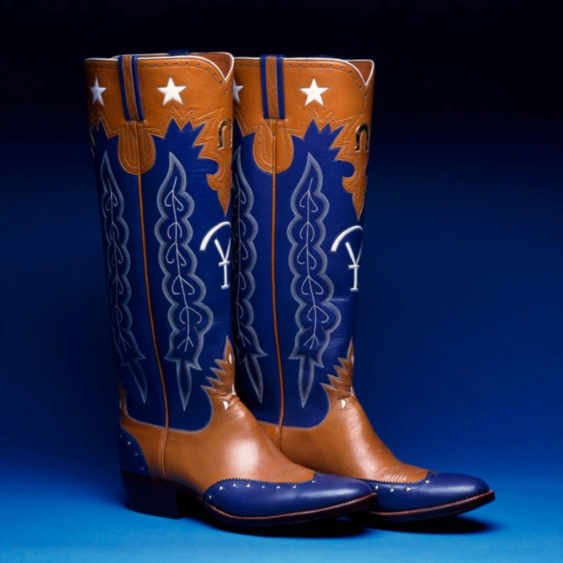 A pair of brown and blue cowboy boots with star and decorative stitching details, set against a dark blue background.