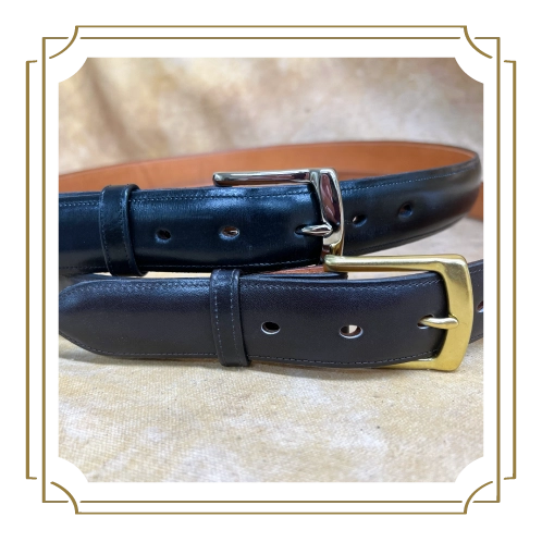 A close-up shot of two black leather belts with gold buckles placed on a beige surface.