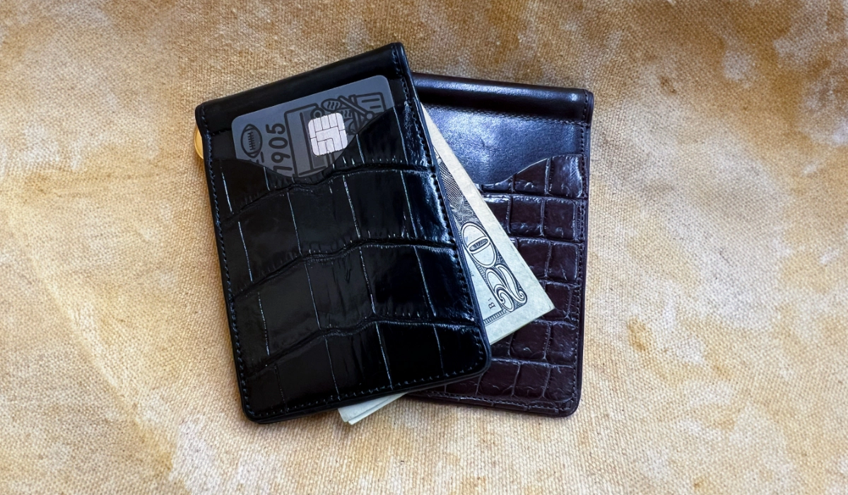 Two leather wallets on a textured surface.