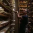 Man selects shoe form in a room lined with shelves containing many shoe forms.